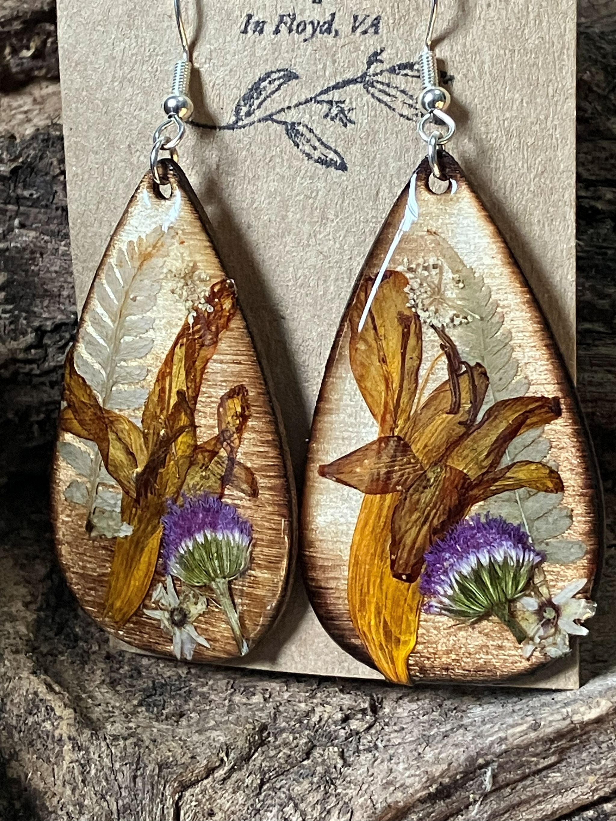 Handmade wooden earrings featuring real crocosmia, fern, and ageratum flowers encased in resin by R & D Floral.