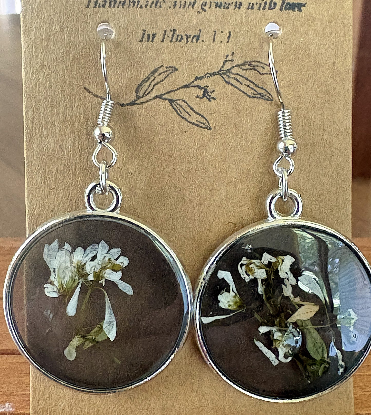 Black and white pressed Euphorbia earrings in round silver metal bezels with resin dome, on a Handmade in Floyd VA kraft card