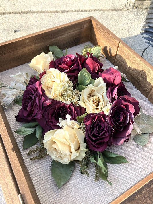 Preserved wedding bouquet with deep burgundy and cream roses arranged in a wooden shadow box frame