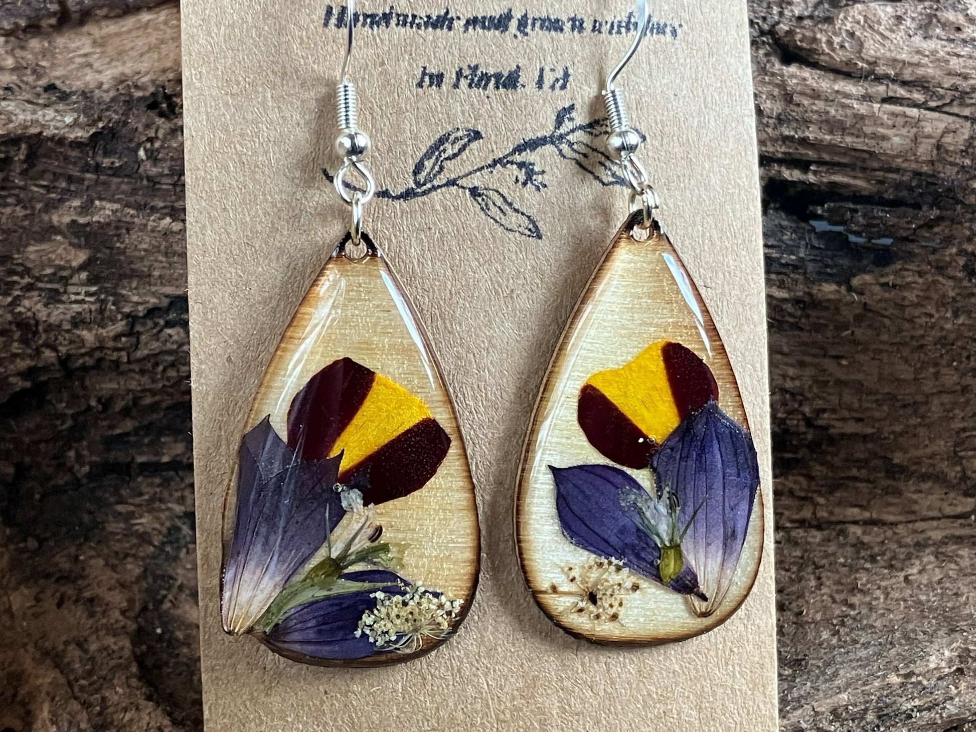 Handcrafted wooden earrings featuring real marigold, salvia, pratia, and Queen Anne’s lace encased in resin by R & D Floral.