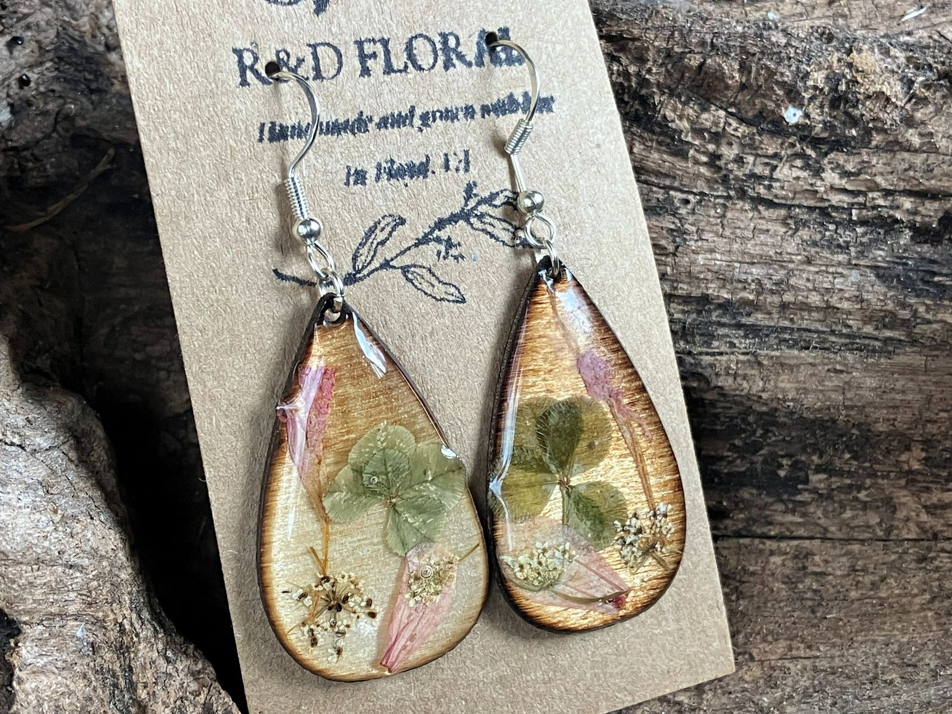 Handcrafted wooden earrings with real four-leaf clover, agastache, and Queen Anne’s lace preserved in resin by R & D Floral.