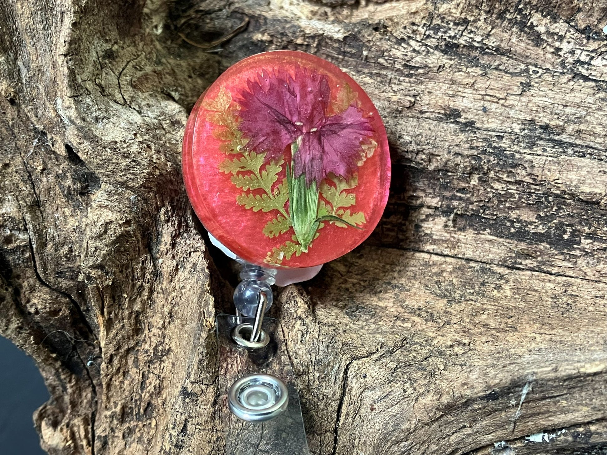 Handmade resin badge reel featuring real Dianthus flowers on a pink background by R & D Floral.