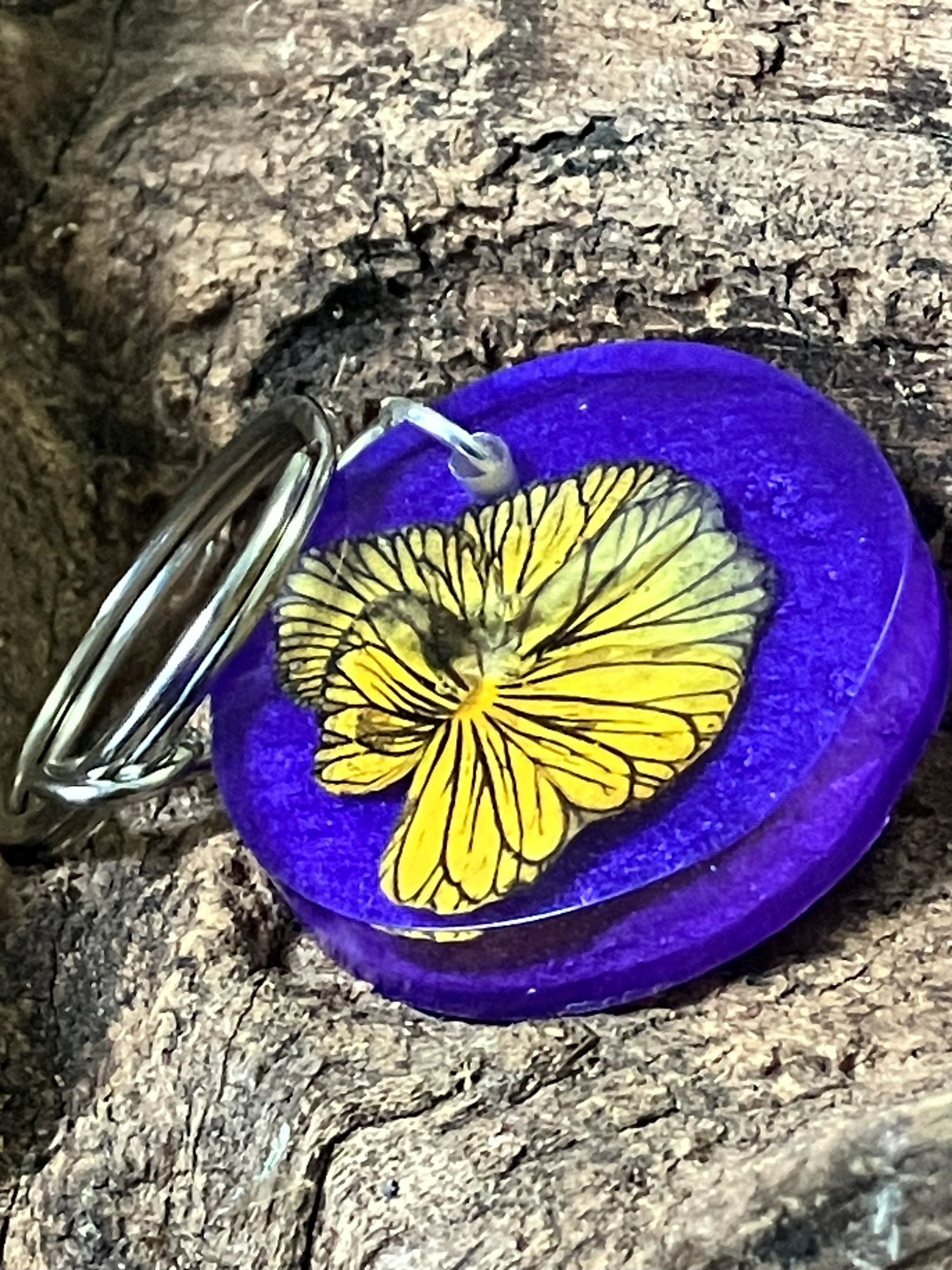 Resin keychain with real Tiger Eye pansy on a blue and purple background, handcrafted by R & D Floral.