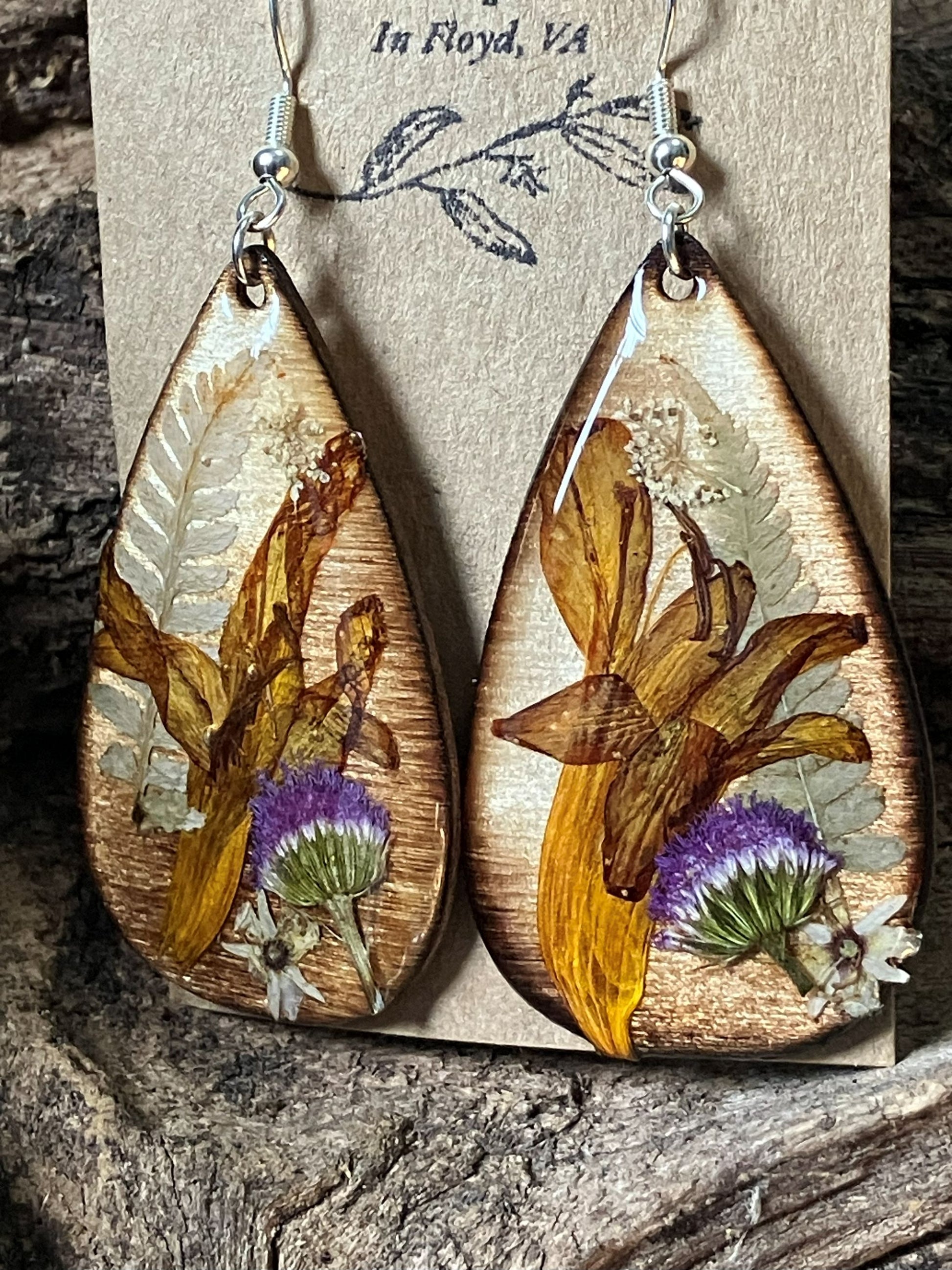 Handmade wooden earrings featuring real crocosmia, fern, and ageratum flowers encased in resin by R & D Floral.