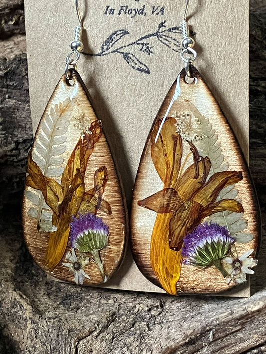 Handmade wooden earrings featuring real crocosmia, fern, and ageratum flowers encased in resin by R & D Floral.