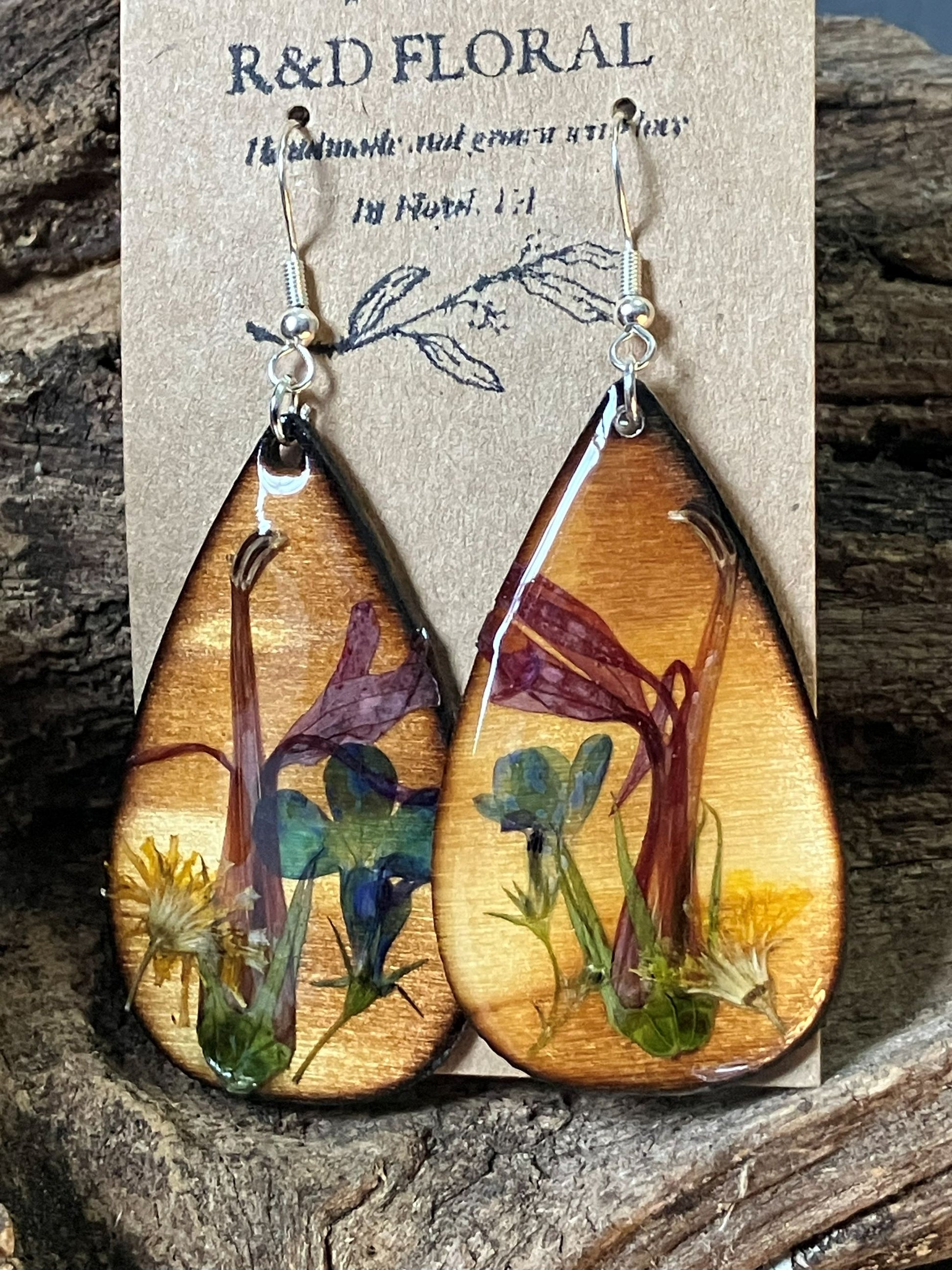 Handcrafted wooden earrings featuring real cardinal flower and dandelion in warm sunset tones preserved in resin by R & D Floral.