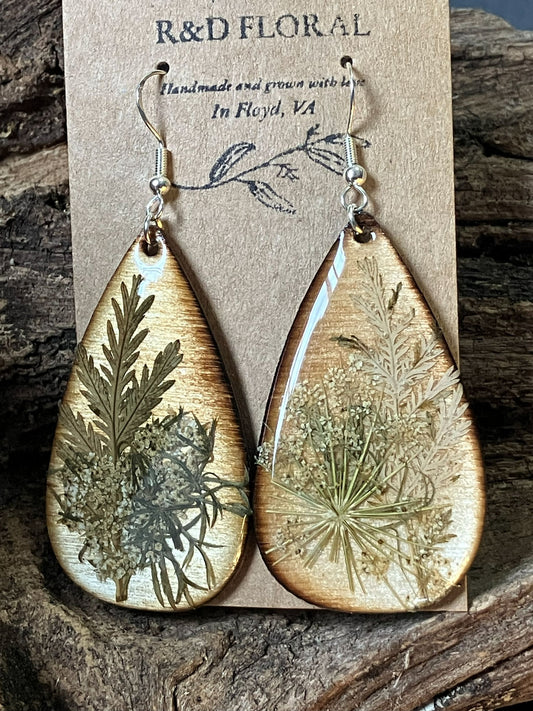 Handcrafted wooden earrings with real wormwood and Queen Anne’s lace flowers resembling a snowy scene, preserved in resin by R & D Floral.