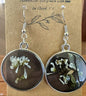 Black and white pressed Euphorbia earrings in round silver metal bezels with resin dome, on a Handmade in Floyd VA kraft card