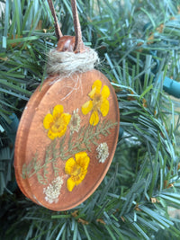 Close-up of Buttercup and Queen Anne's Lace pressed flower ornament in copper resin