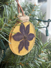 Close-up of pressed clematis flower ornament in gold resin