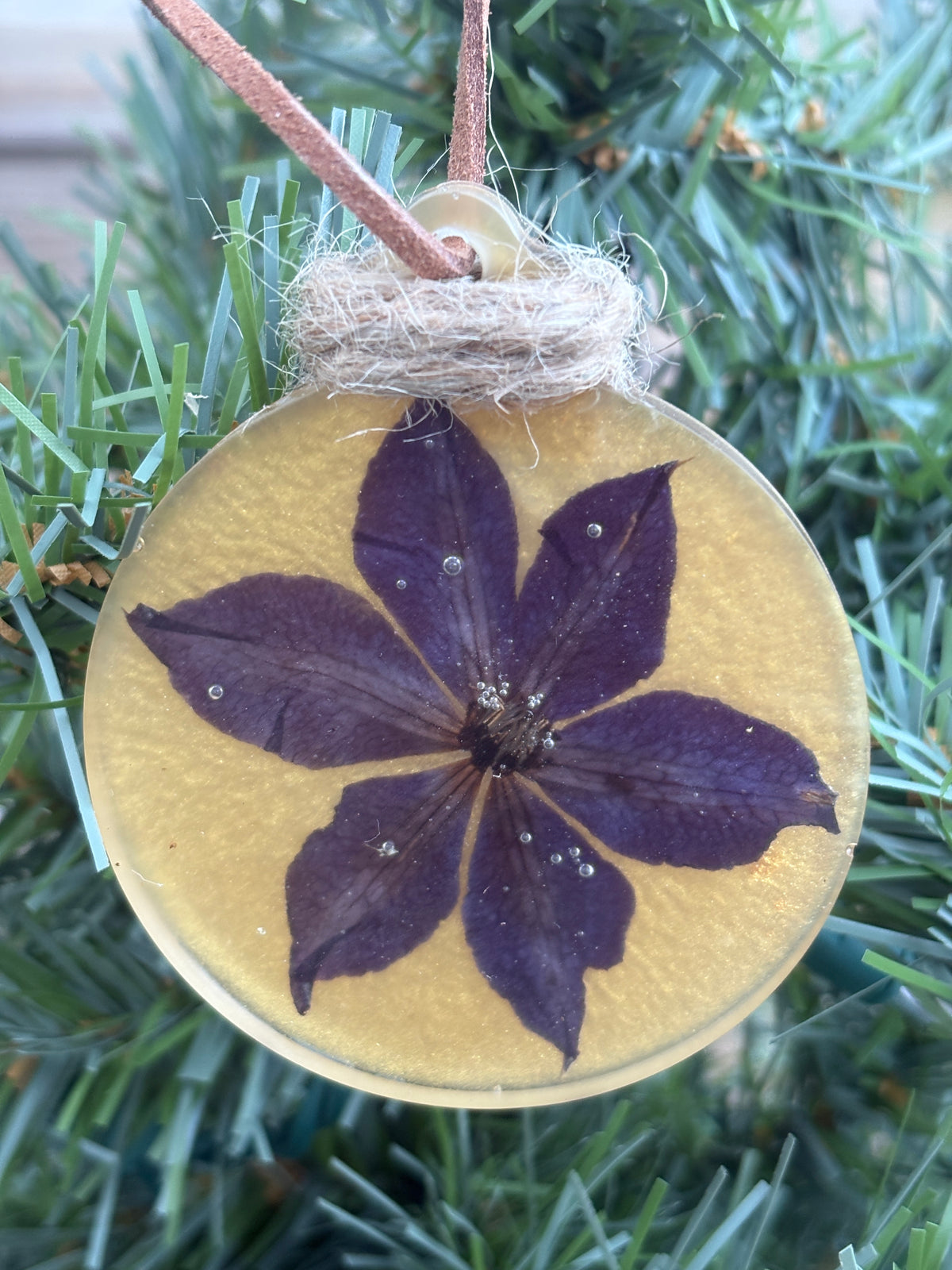 Angled view of pressed clematis flower ornament in gold resin