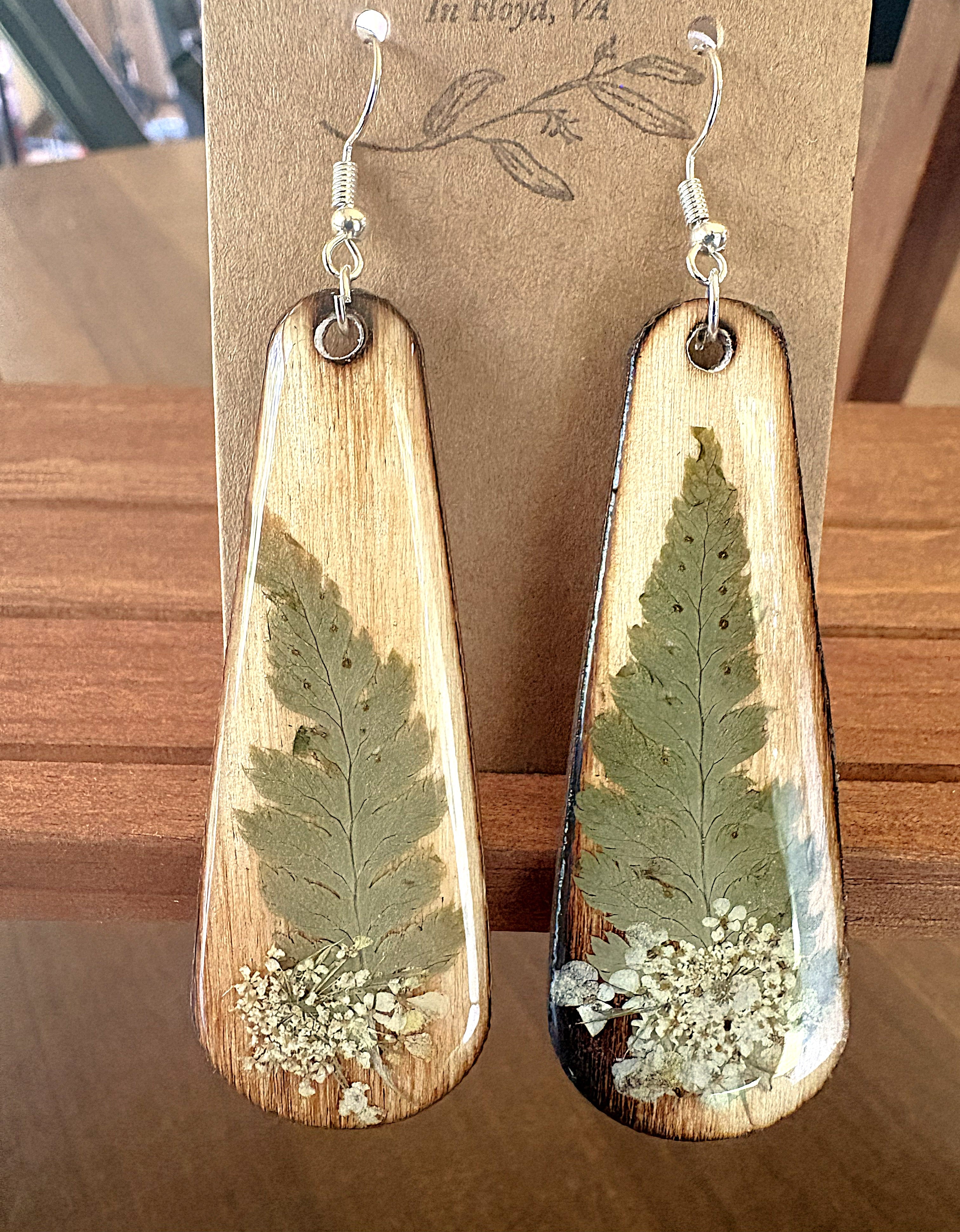 Fern and Queen Anne's Lace wooden teardrop earrings on wood grain background
