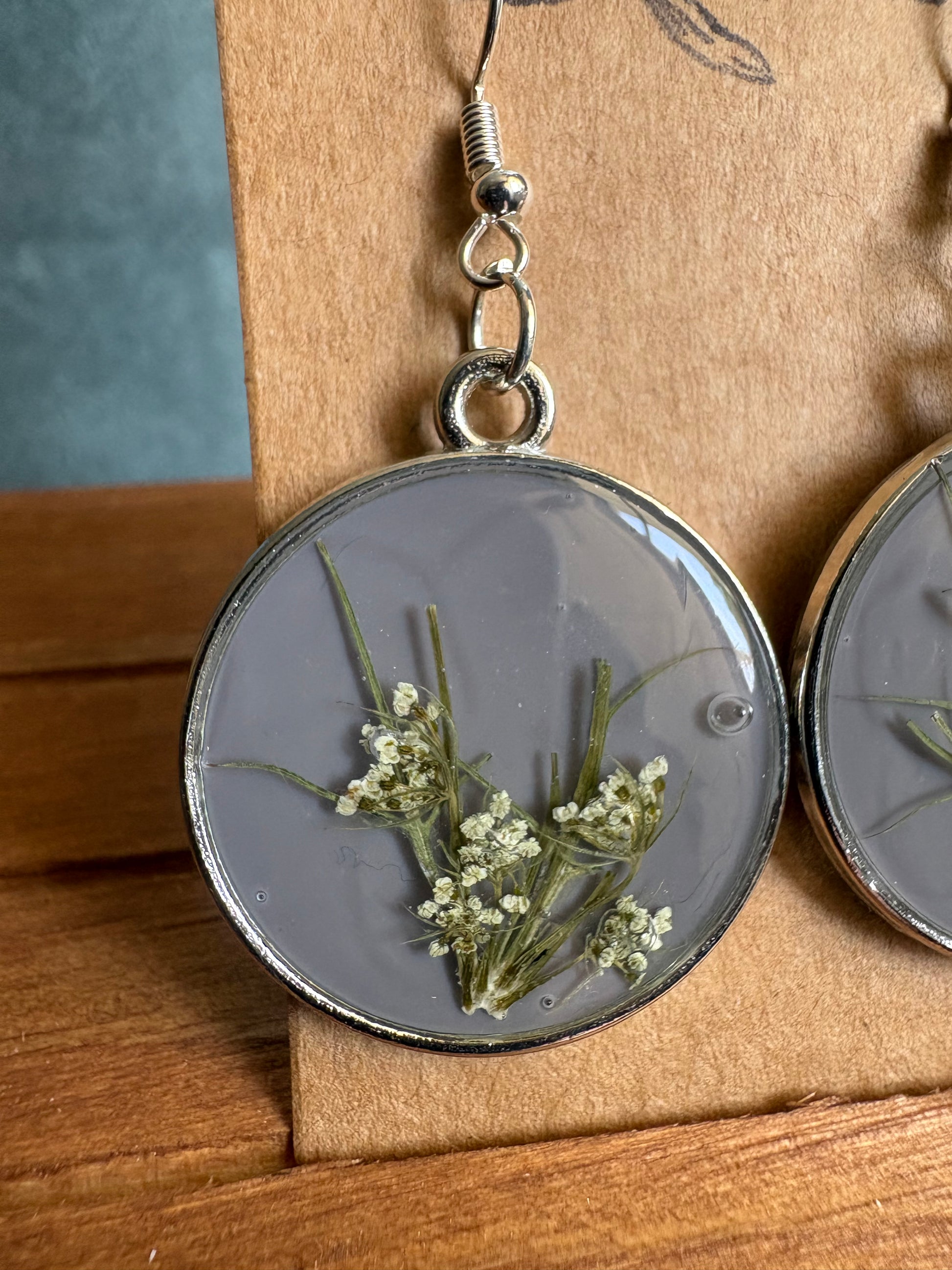 Single grey resin round earring with silver fish hook wire and pressed Queen Anne's Lace