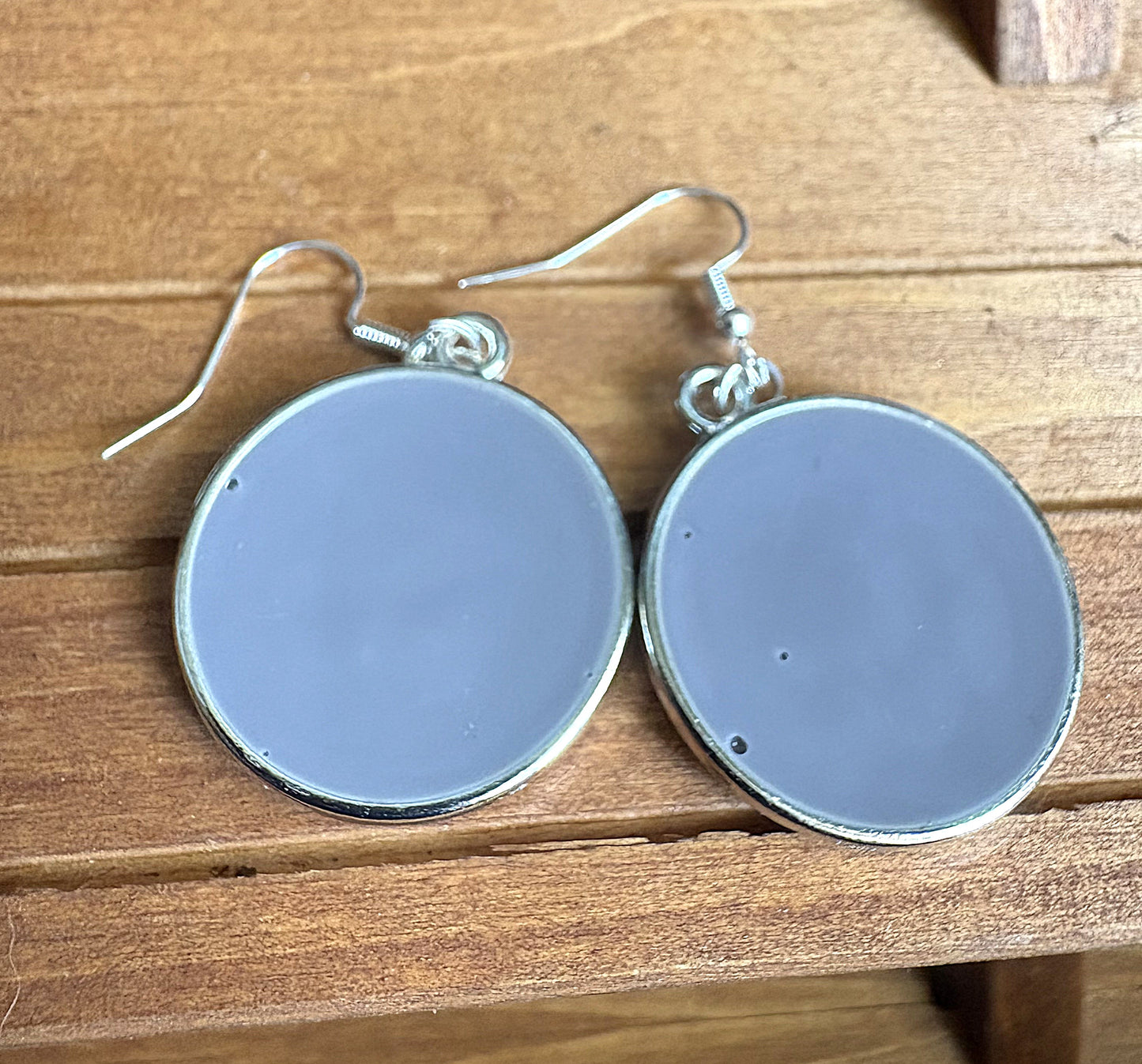 Back view of grey resin round earrings showing smooth polished resin finish