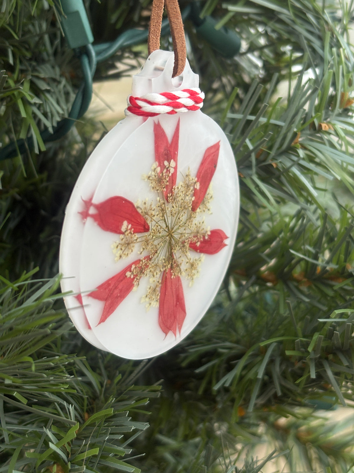 Close-up of red Salvia and Queen Anne's Lace snowflake pattern in white resin ornament