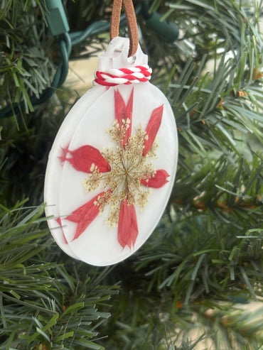 Close-up of red Salvia and Queen Anne's Lace snowflake pattern in white resin ornament
