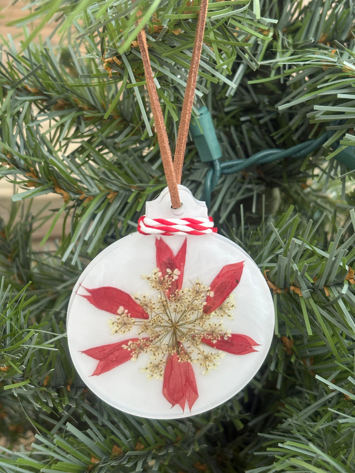 Red Salvia and Queen Anne's Lace pressed into a snowflake pattern in white resin on red and white twine
